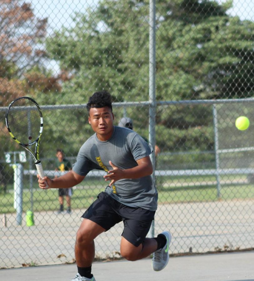 Making a forehand swing, senior July Moo returns the ball to his Omaha Central opponent at is Sept. 20, home meet.  “My goal for senior year was to really focus on my matches, and I have accomplished that this season,” Moo said.