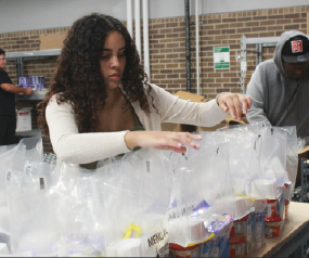 After the truck is unloaded and each pallet is in its assigned location, junior Perla Gonzales and other TDL students unwrap the pallets and start to sort the food into bags which will later be air-sealed before being packaged in boxes for shipment to schools.