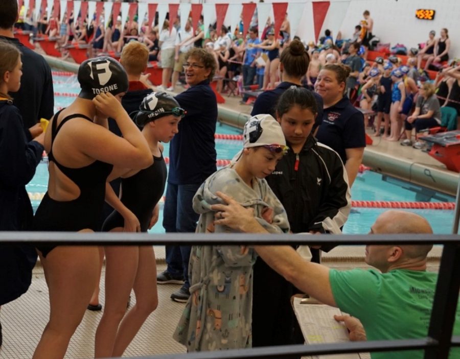 At a local swim meet, Drew Butler, new Bryan head coach and founder of the Omaha Swim Federation, goes over meet events with his athletes.