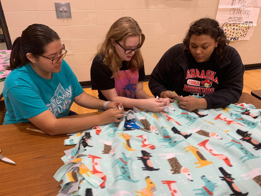 NHS members help tie the fleeces for the blankets. At the bi-annual Project Linus this year, students and past alumni helped make over 900 blankets that are going to be donated to different organizations for people in need.