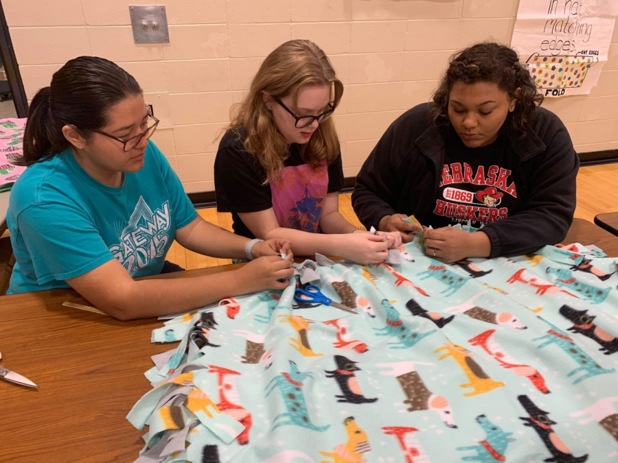 NHS+members+help+tie+the+fleeces+for+the+blankets.+At+the+bi-annual+Project+Linus+this+year%2C+students+and+past+alumni+helped+make+over+900+blankets+that+are+going+to+be+donated+to+different+organizations+for+people+in+need.