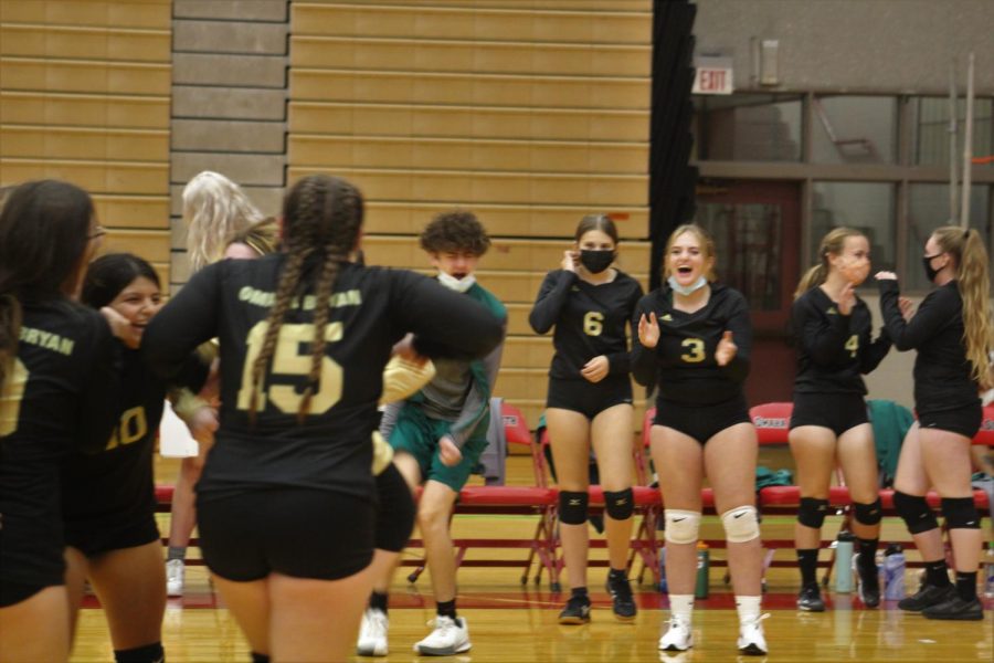 After the girls varsity volleyball team wins one of the sets they triumphantly run back to their team, whore waiting for them in excitement.