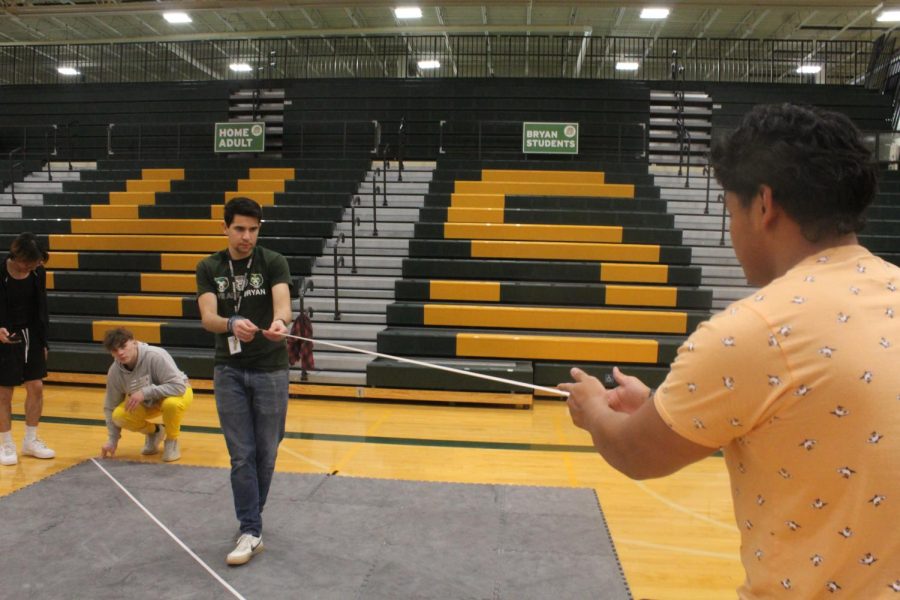 Math teacher Dario Gudino-Garcia helping sophomore Paw Eh Klay Soe place line up a piece of tape to be placed down.