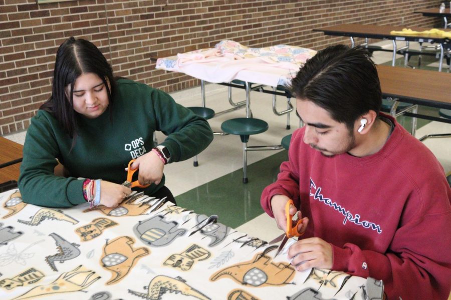 Seniors Yulissa Villagomez and Erick Barrera Bustamante cut strips of the fleece to tie together to create a blanket. 