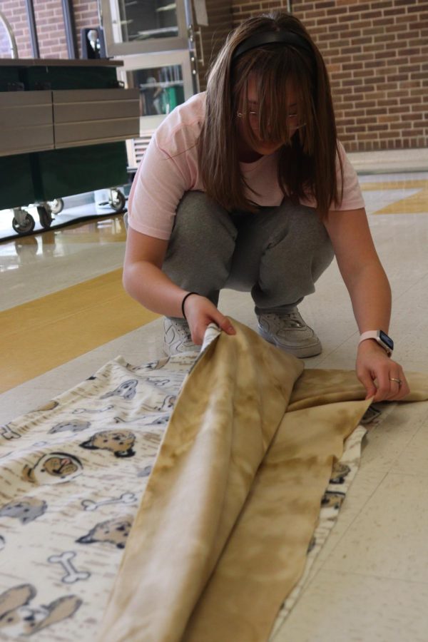 Senior Macy Hutfless lines up the two layers of fleece to create a blanket. 