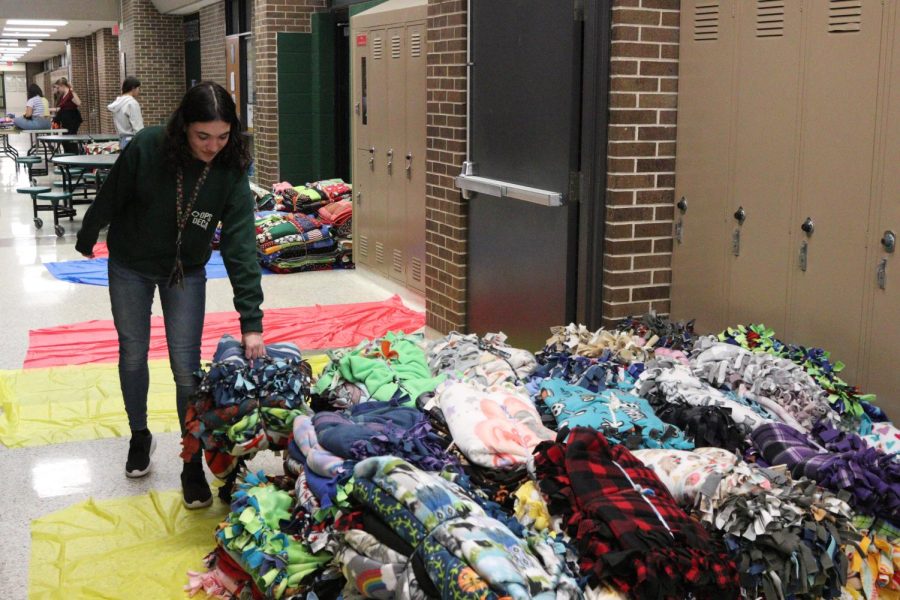 Junior Kaydance Jones brings a bundle of completed blankets into a pile. 
