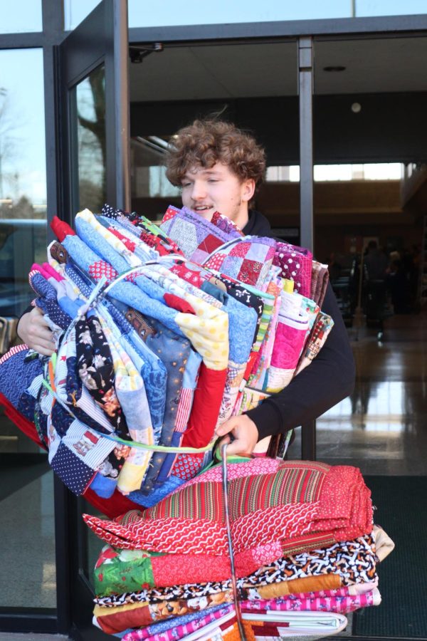 Senior Cole Rickley carries a few bundles of blankets to a car.
