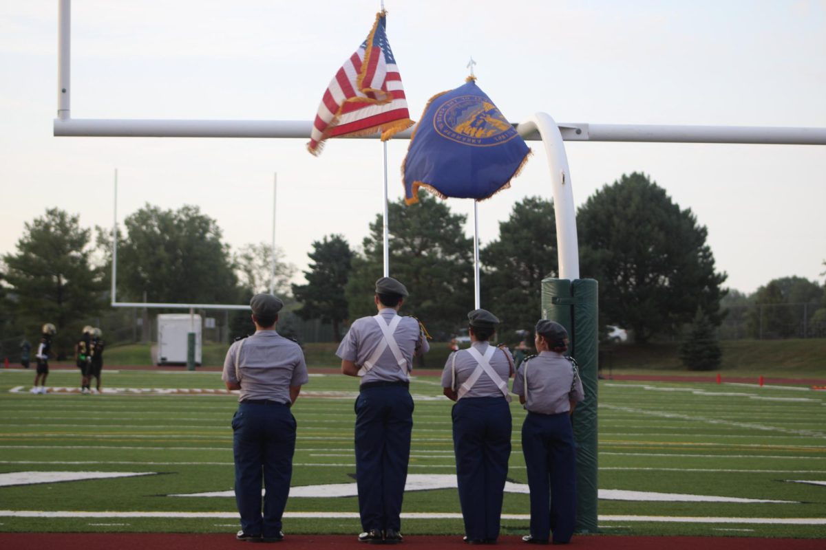 The JROTC color guard stands still, awaiting their signal, before marching on the field to present the colors. 